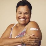 Senior woman smiling with bandaid on vaccine injection