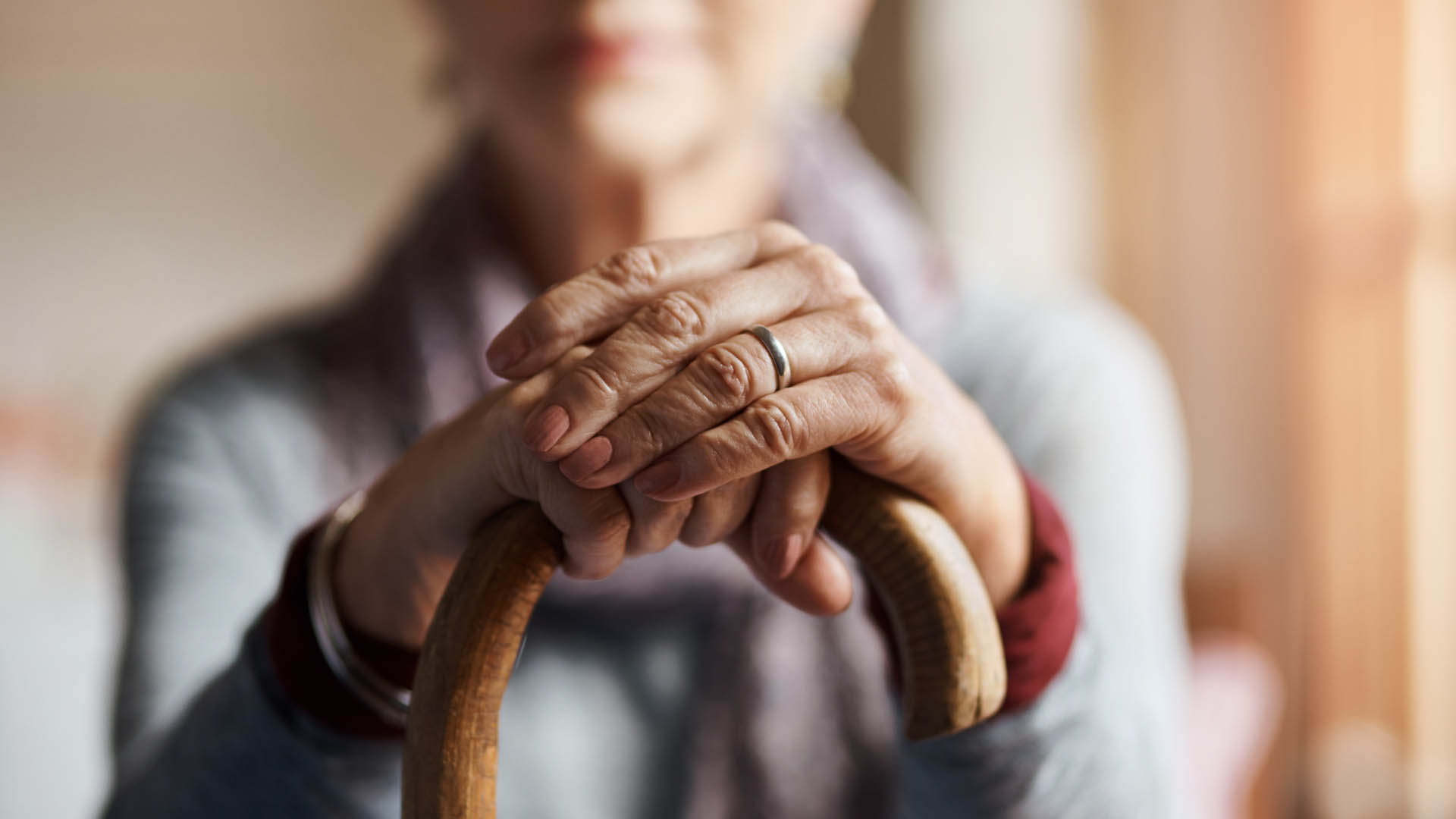 close up of elderly hands holding a cane