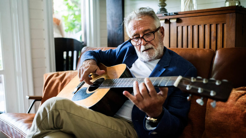 retired man learning to play guitar