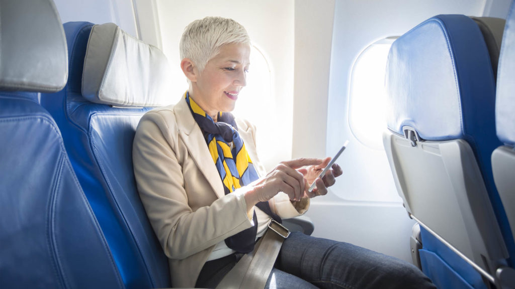 woman seated on a plane checking her phone