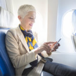 woman seated on a plane checking her phone