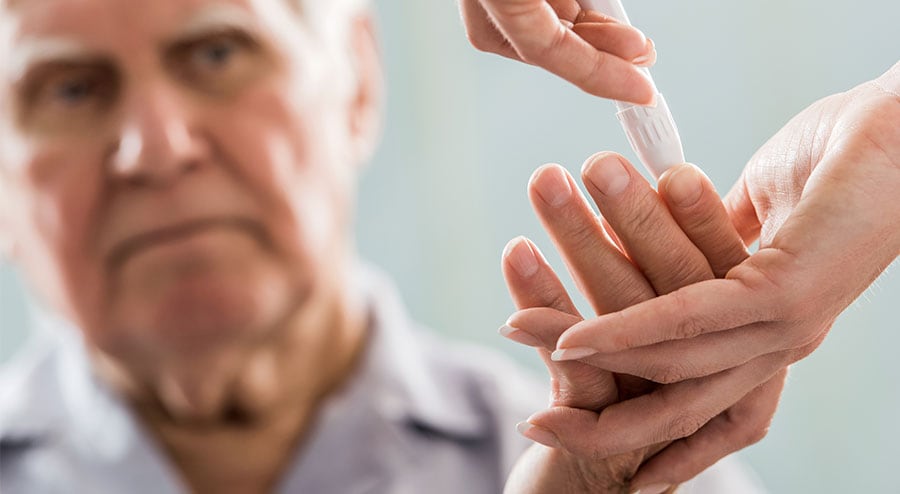 Aging male taking a diabetic test by finger prick