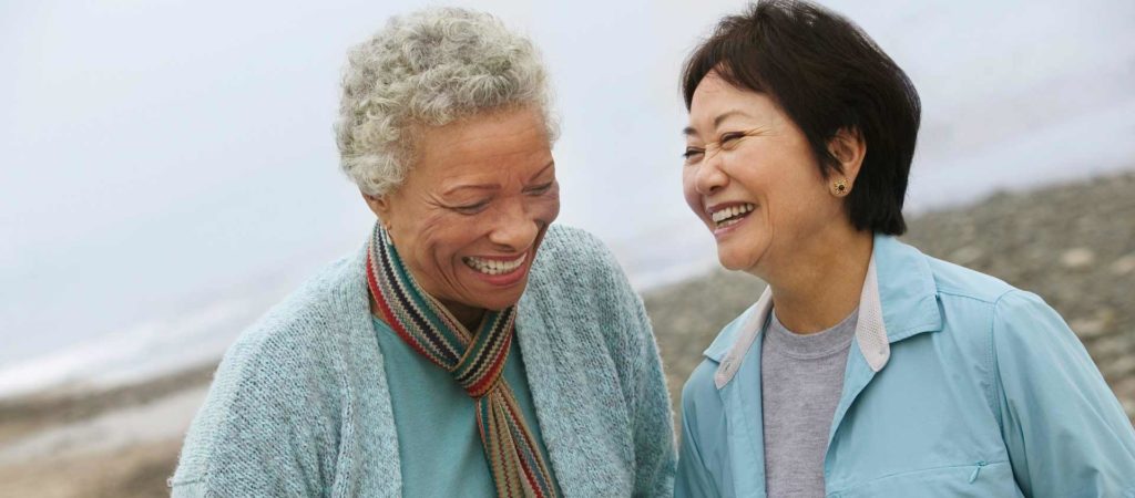 Two middle aged women laughing together. 