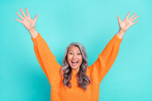 Portrait of attractive amazed grey-haired woman rising hands up having fun rejoicing isolated over bright teal turquoise color background